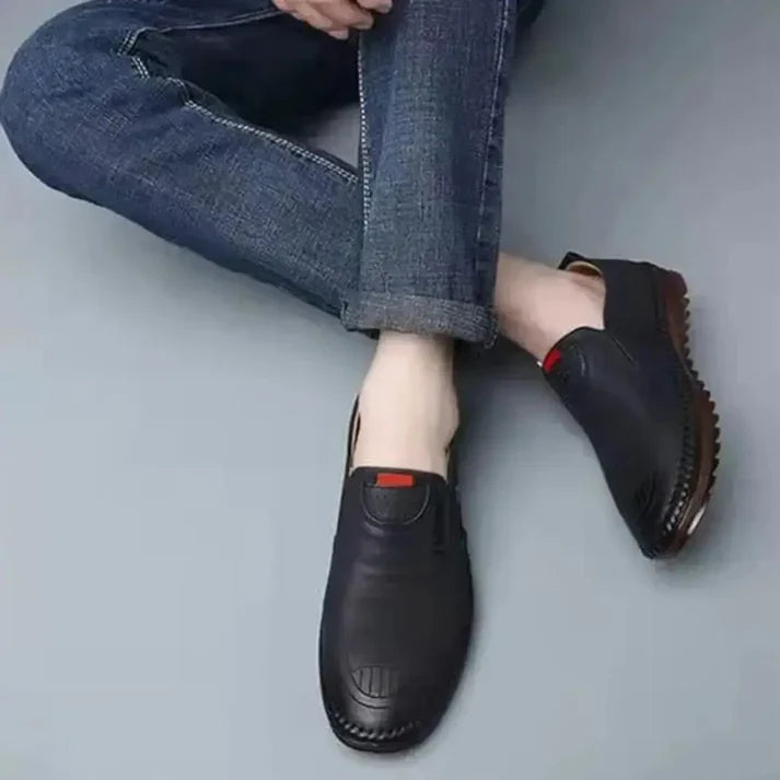 A pair of black men's leather slip-on shoes showing the minimalist design and flexible sole