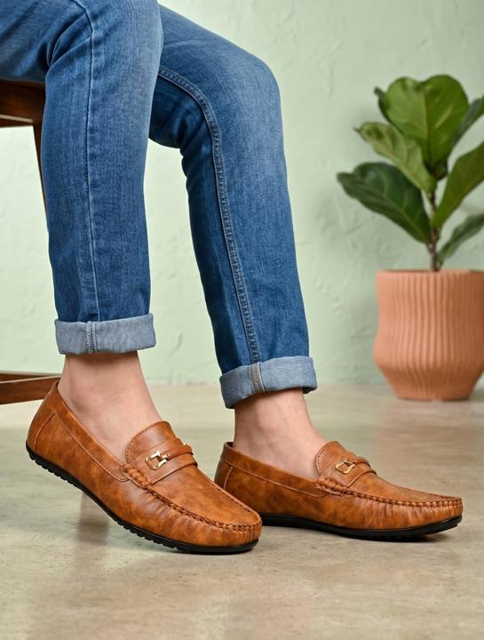 A pair of tan synthetic leather loafers with a metallic horsebit detail on the vamp and a classic apron toe