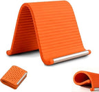 A flexible silicone and aluminum phone stand bent at an angle on a desk