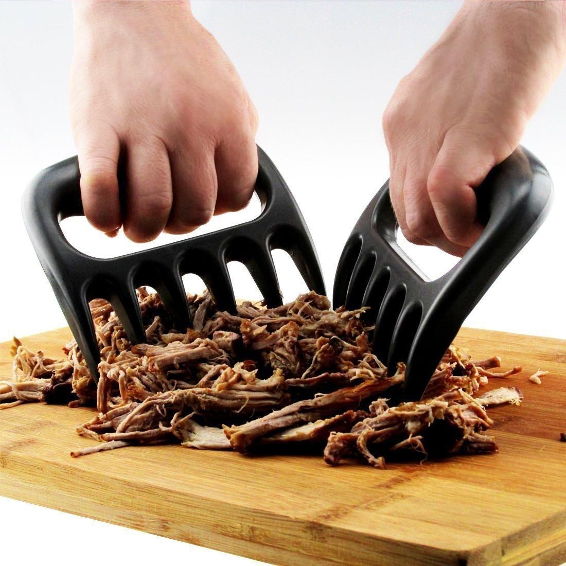 Pair of black bear claw-style meat shredders on a wooden surface