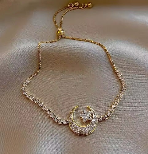 A brass moon and star bracelet on a neutral background