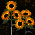 A decorative solar-powered sunflower light with a stainless steel stem placed in a garden.