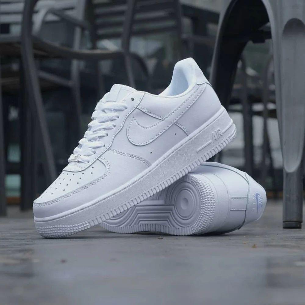 A pair of white men's perforated casual sneakers made of faux leather