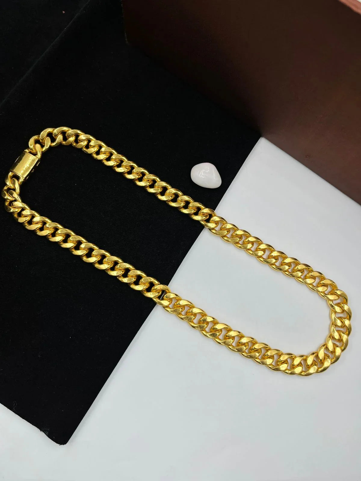 A close up view of a golden-toned brass chain for men against a plain background